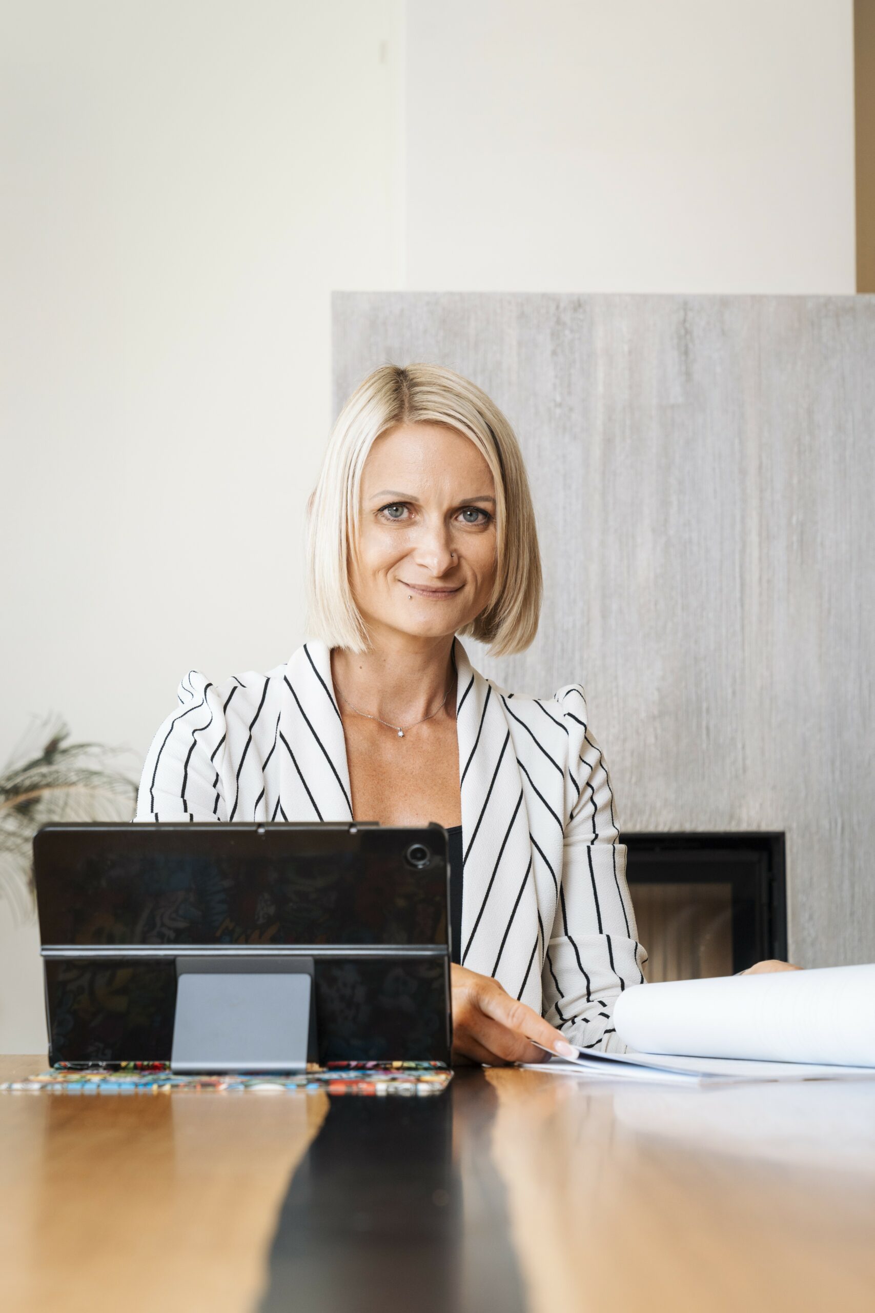 Sandra Melin, MBA, sitzt mit Tablet und Unterlagen am Schreibtisch und berät zu Webseitentexten, Neuromarketing und KI Sichtbarkeit für KMU.